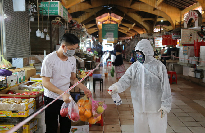 Người dân trang bị đồ bảo hộ, kính ngăn giọt bắn và chai xịt khuẩn khi đi mua hàng ở chợ.