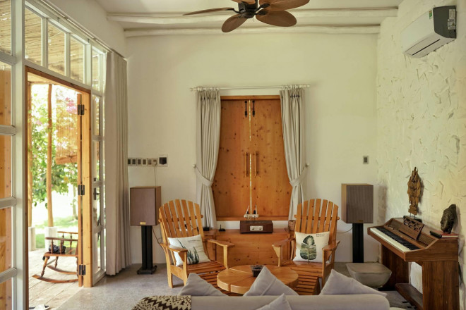 Nội thất của ngôi nhà gồm 2 gam màu chủ đạo là trắng và nâu gỗ tự nhiên. Tại phòng khách bày biện bộ bàn ghế gỗ, đàn piano, một vài vật dụng trang trí,.. theo lối sắp xếp cân đối, gọn gàng.