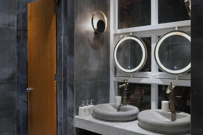 Không gian nhà tắm được trang trí thêm những chiếc đèn thả hình tròn và ô cửa thoáng rộng kết nối với bên ngoài.