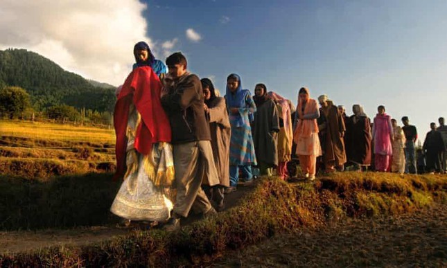 Một cô dâu Kashmir khoác trên mình chiếc khăn choàng đỏ, đồng hành cùng gia đình và bạn bè đến nhà chú rể để bắt đầu buổi lễ