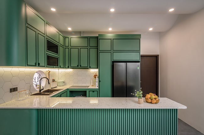 Phòng bếp chính là không gian được gia chủ cực kỳ tâm đắc với hệ tủ gỗ mang sắc xanh ấn tượng, mặt bếp sử dụng đá Terrazo có hoa văn bắt mắt. Tổng thể gian bếp gọn gàng, ngăn nắp và đầy đủ các hệ tủ phục vụ cho việc lưu trữ đồ đạc. 
