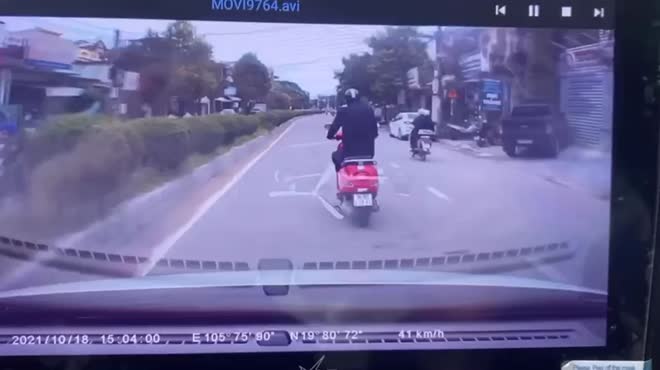 Nam tài xế điều khiển xe máy vespa di chuyển lượn trước đầu ô tô.