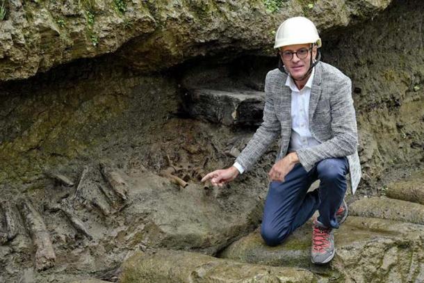 Một nhà khảo cổ bên bộ hài cốt vừa lộ ra giữa lớp tro bụi cổ đại - Ảnh: ANSA