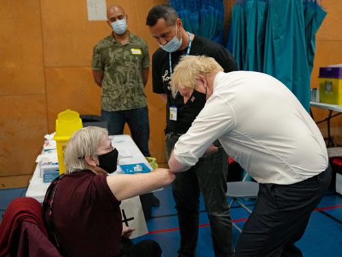 Thủ tướng Anh Boris Johnson giao lưu với cụ Nitza Sarner, 88 tuổi, trong khi cụ chờ được tiêm tăng cường ở thủ đô London hôm 22-10 Ảnh: REUTERS