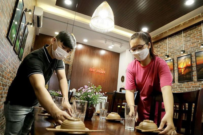 Nhân viên một nhà hàng ở quận Gò Vấp (TP.HCM) sửa soạn các bàn ăn chờ được phục vụ khách ăn uống tại chỗ trở lại vào chiều 25-10. Ảnh: HOÀNG GIANG
