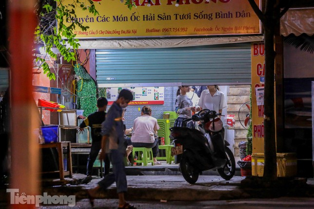Cửa hàng ăn trong một ngõ phố Hoàng Cầu (quận Đống Đa, Hà Nội) đóng nửa vời, khách vẫn ung dung ăn uống bên trong.