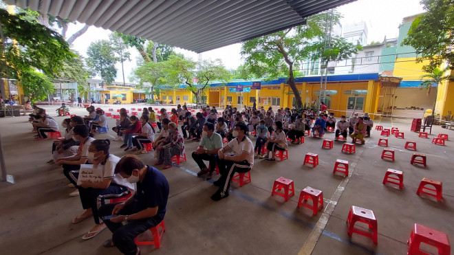 Phụ huynh và học sinh trường THPT Ernst Thalmann (quận 1, TP HCM) ngồi chờ khai báo trước tiêm