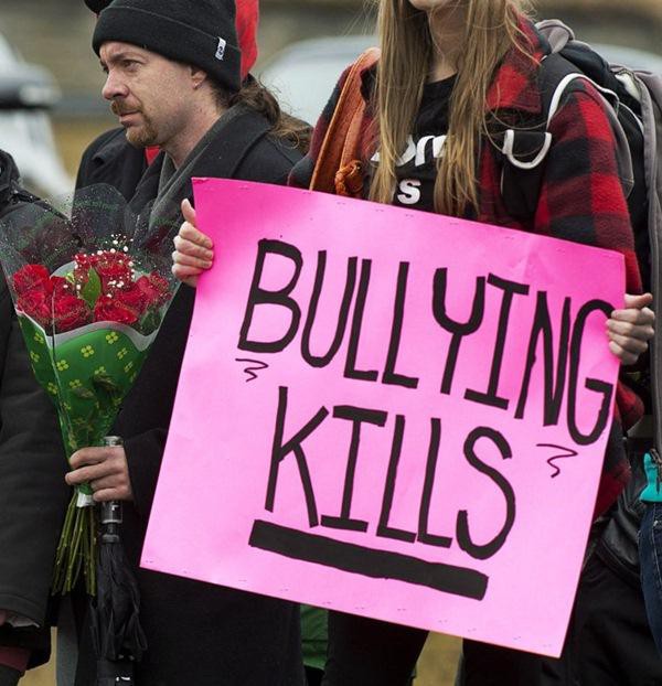 Một cô gái cầm tấm giấy ghi: "Việc bắt nạt có thể giết người". Ảnh: The Star.