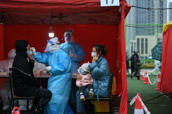 Nhân viên y tế mặc đồ bảo hộ đang xét nghiệm COVID-19 cho người dân. Ảnh: Reuters