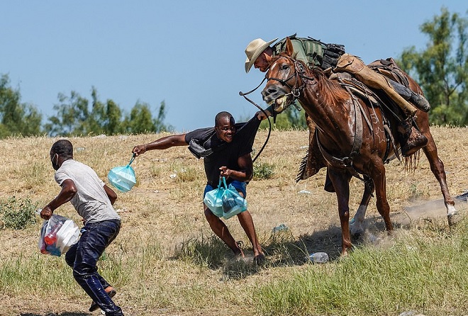 Mirard Joseph (áo đen, giữa ảnh) bị một đặc vụ thuộc lực lượng kỵ binh tuần tra biên giới Mỹ túm áo hồi cuối tháng 9. Ảnh: Getty