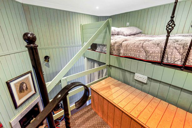 Khu vực gác lửng được hoàn thiện bằng ván gỗ màu xanh ô liu và đèn tường phong cách cổ điển. Đi xuống cầu thang là tầng hầm dài 3,9m, với khu vực sinh hoạt nhỏ, nhà bếp và phòng tắm được trang bị đồ nội thất cá tính.
