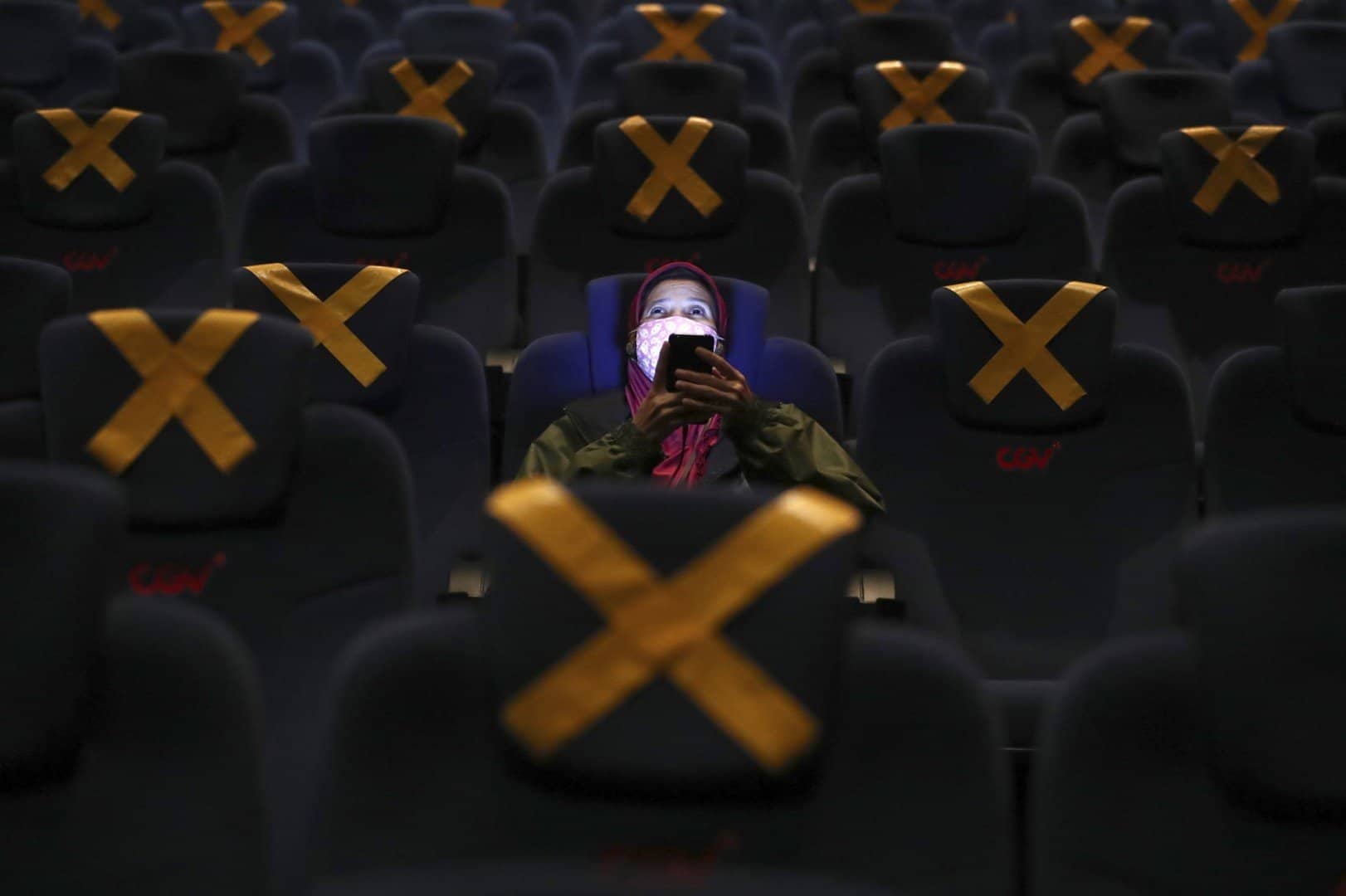 Một người dân sử dụng điện thoại trước giờ chiếu phim ở rạp trong ngày đầu tiên Indonesia cho các rạp chiếu phim hoạt động trở lại ở thủ đô Jakarta hôm 16/9. Một điều dễ nhận thấy là những chiếc ghế được đánh dấu để đảm bảo khoảng cách an toàn trong dịch Covid-19. Ảnh: AP