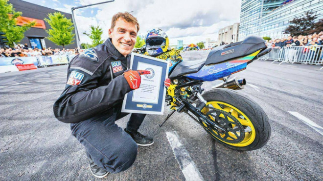 Arūnas Gibieža bên chiếc xe và chứng nhận kỷ lục thế giới mới về kỹ năng đi xe máy bốc đầu buông hai tay xa nhất