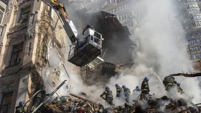 Lính cứu hỏa làm việc tại một tòa nhà bị hư hại sau cuộc tập kích ở Kiev. Ảnh: AP.