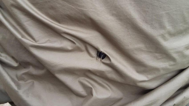 Viên đạn xuyên thủng áo khoác cán bộ bảo vệ rừng. Ảnh: VT