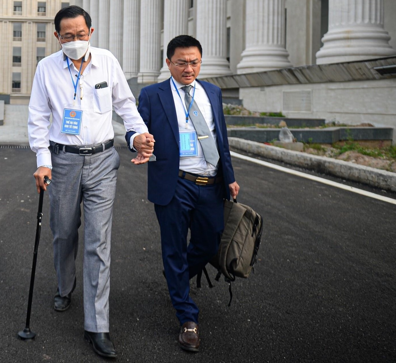Cựu Thứ trưởng Cao Minh Quang được luật sư dắt tay, chống gậy đến phiên toà ngày 21/11.