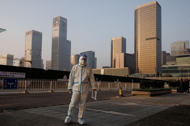 Một nhân viên y tế đứng trước một tòa nhà ở Bắc Kinh (Trung Quốc). Ảnh: Reuters