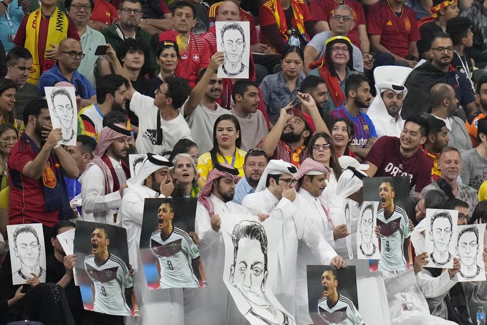 Một nhóm cổ động viên Qatar mang theo ảnh cựu tuyển thủ Đức Mesut Özil và lặp lại hành động dùng tay che miệng giống các cầu thủ Đức. Ảnh: AP