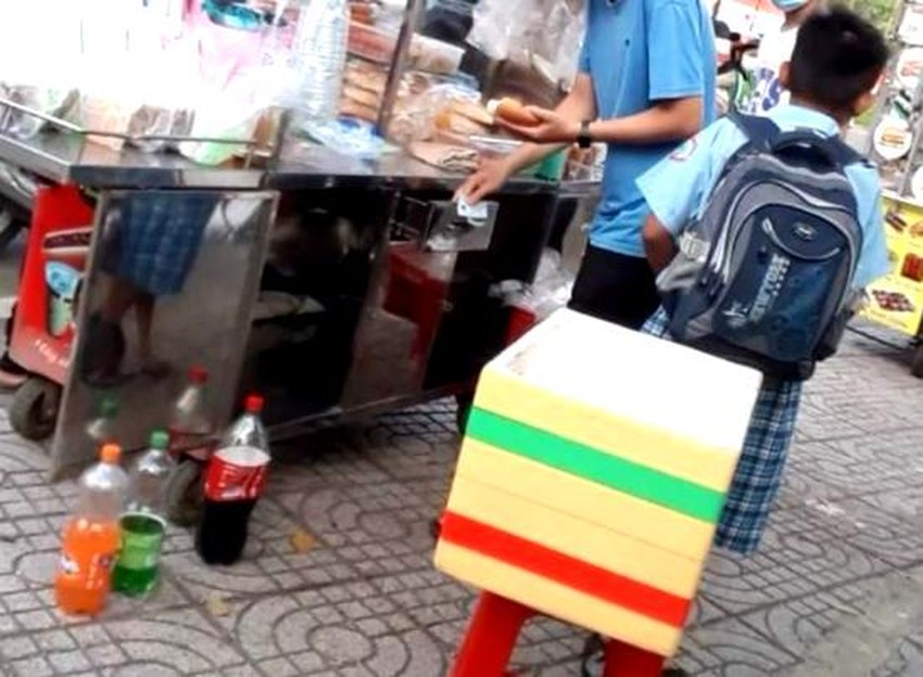 Người bán bánh mì trước cổng Trường Tiểu học Ngô Quyền, quận Bình Tân dùng tay không cầm thức ăn và tiền. Ảnh: TRẦN NGỌC