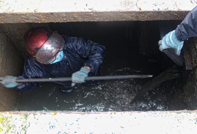 Công nhân ngâm mình trong bùn đen nạo vét, khơi thông cống trên địa bàn quận Cẩm Lệ. Ảnh: Giang Thanh.