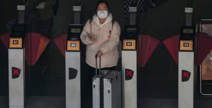 Một người phụ nữ đeo khẩu trang ra khỏi ga tàu điện ngầm ở Bắc Kinh, Trung Quốc vào ngày 13-12. Ảnh: AP