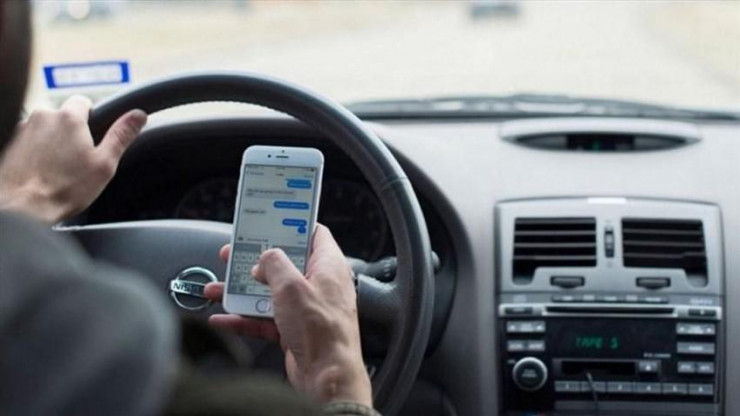 Vừa lái ô tô vừa xem điện thoại có thể bị phạt tiền kèm bị tước bằng lái xe. (Ảnh minh hoạ)