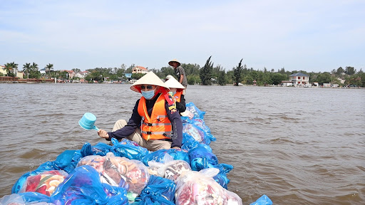 Hai anh chị không ngại lội nước, chèo thuyền để mang quà đến cứu trợ bà con vùng lũ.