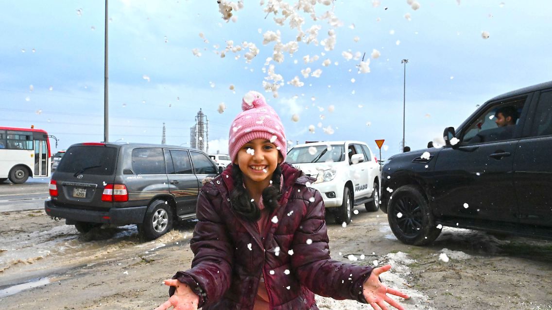 Một bé gái Kuwait tung nắm đá, đùa nghịch sau trận mưa đá. Ảnh: Tân Hoa xã