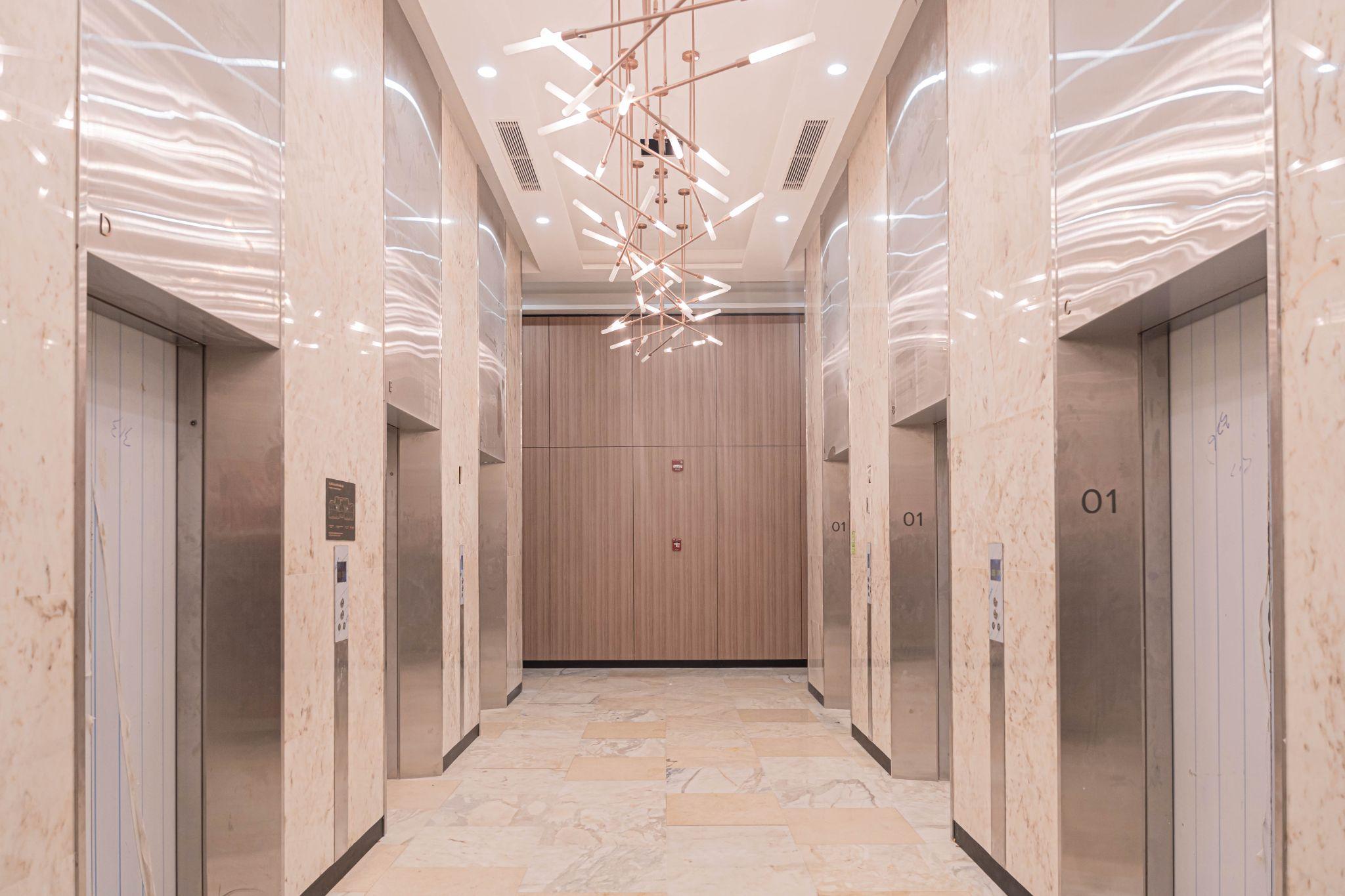 Khu vực sảnh thang máy sang trọng lịch sự với trần cao, ánh sáng đầy đủ.