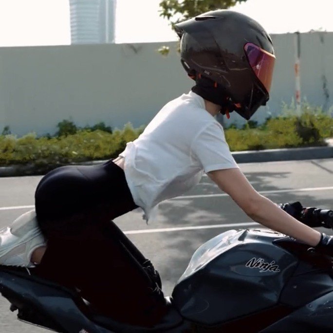 Người phụ nữ quỳ lên mô tô để chạy xe.