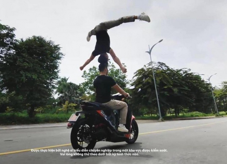 Hai nghệ sĩ biểu diễn chồng đầu khi lái xe máy điện. Ảnh: Cắt từ clip