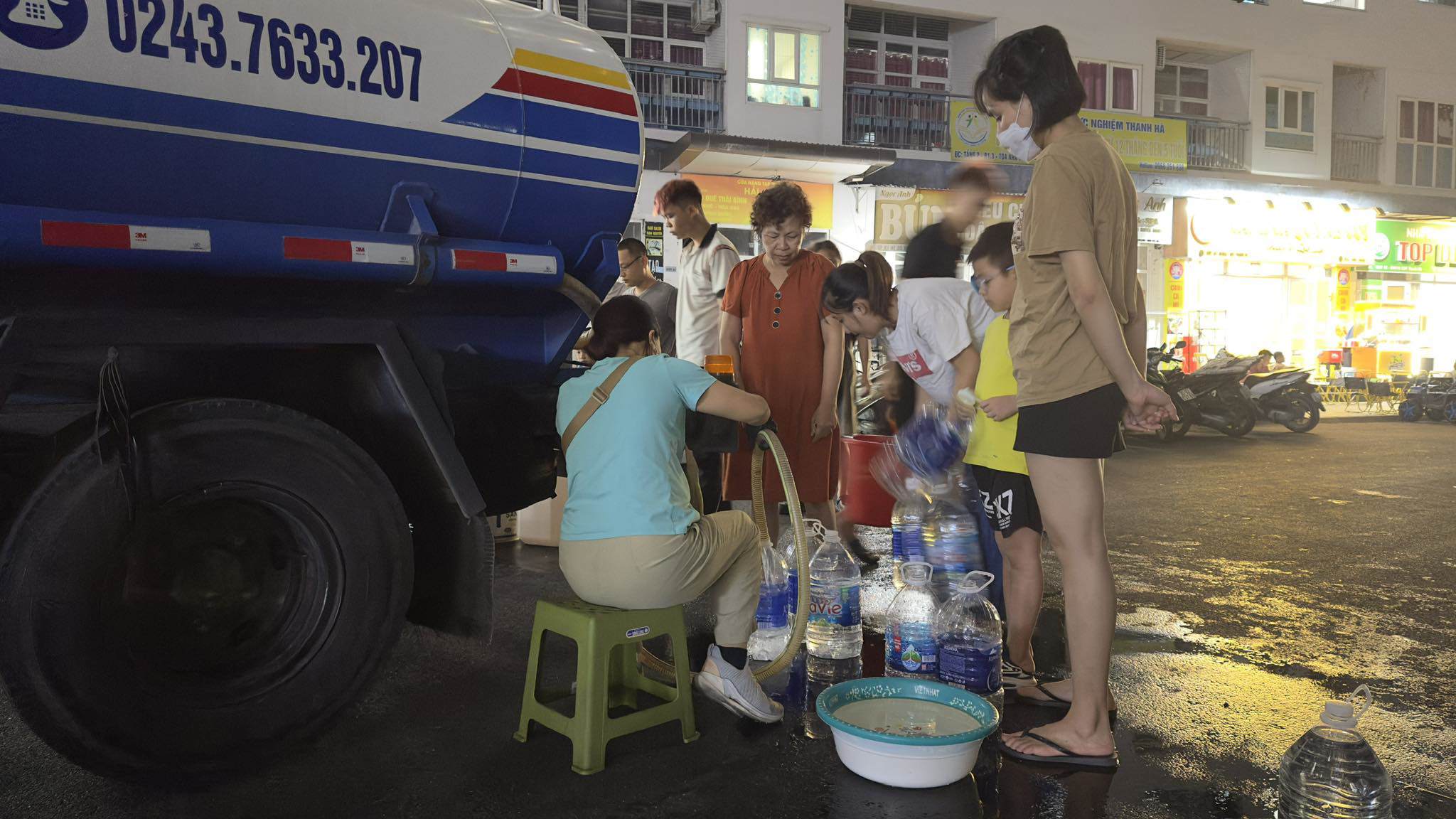 Cư dân cụm chung cư HH02-B1.4, HH03-B1.3 lấy từng cốc nước từ xe bồn về sử dụng.