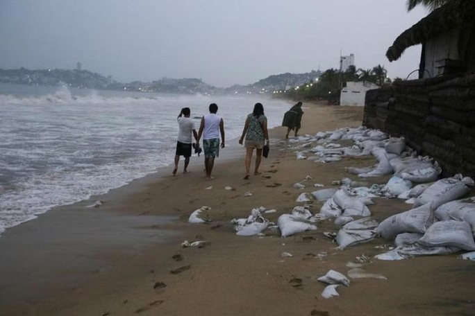 Người dân đi bộ dọc bãi biển khi cơn bão Otis đang hướng tới khu nghỉ dưỡng nổi tiếng Acapulco của Mexico. Ảnh: REUTERS/Javier Verdin