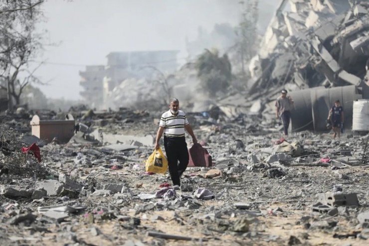 Người dân phía bắc Dải Gaza đi qua khu vực các tòa nhà bị phá hủy vào ngày 20-10. Ảnh: AP