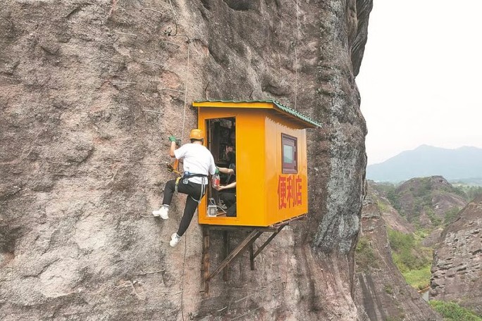 Một người leo núi đang mua sắm tại cửa hàng tiện lợi trên vách đá cheo leo tại khu danh lam thắng cảnh Shiniuzhai. Ảnh: China Daily