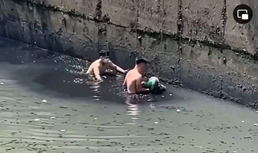 Thượng úy CSGT cùng với người dân đã trèo xuống kênh, đưa ông V lên bờ. Ảnh cắt từ clip