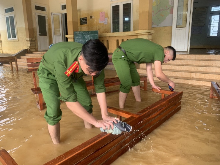 Chiến sĩ công an lau chùi bàn ghế bị ngập lụt.