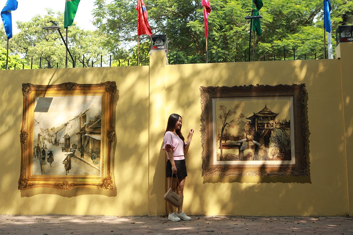 “Khi đi qua đây, thấy những bức tranh về Hà Nội xưa rất đẹp nên tôi dừng xe, đứng ngắm và chụp ảnh với những bức họa yêu thích. Khi ngắm nhìn những bức tranh, tôi&nbsp;thấy dấu ấn Thủ đô 1.000 năm tuổi trong đó”, chị Lê Thị Hiền chia sẻ.
