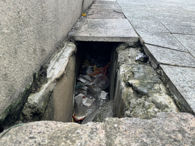 Dưới lớp gạch bong tróc là cống với đầy rác thải