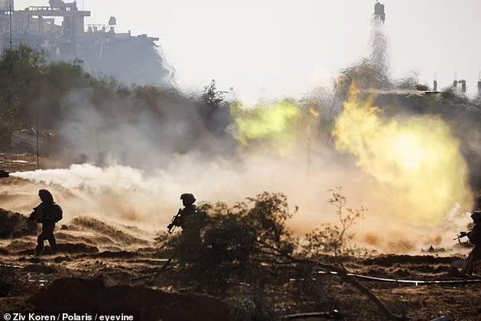 Binh sĩ Israel đi dọc chiến tuyến ở Dải Gaza khi một chiếc xe tăng Merkava của Israel phun khí gas phía sau - Ảnh: Ziv Koren