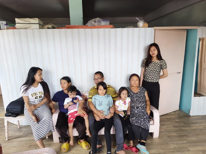 Ông Nunparliana, người chủ gia đình lớn nhất thế giới hiện tại, cùng hai người vợ ngồi hai bên trên ghế dài và một số trong số 13 người con của ông. Ảnh: Straits Times