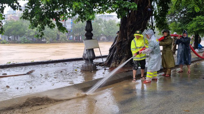 Lực lượng công an dọn dẹp bùn sau lũ trên đường phố ở tỉnh Thừa Thiên - Huế. Ảnh: QUANG NHẬT
