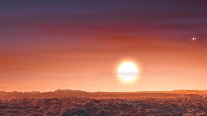Quang cảnh trên hành tinh LTT 1445 Ac với ba "mặt trời đỏ", một cái ở gần và hai cái ở xa, là ba ngôi sao của hệ sao LTT 1445 - Đồ họa: NASA