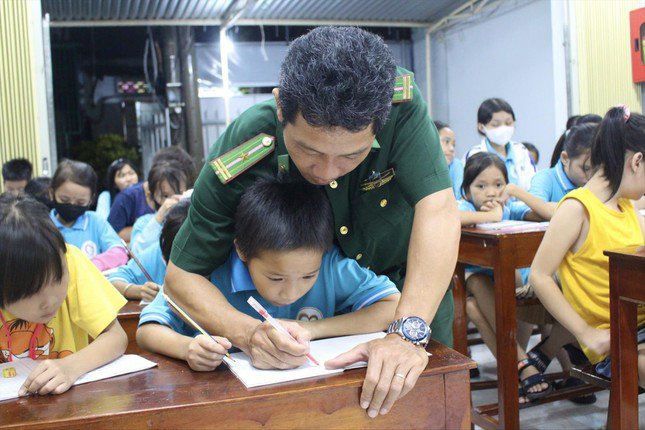 Thiếu tá Nguyễn Văn Tưởng ân cần kèm từng nét chữ cho các em tại lớp học tình thương. Ảnh: KHÁNH NGUYÊN