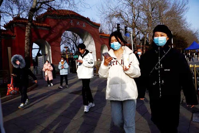 Người dân đeo khẩu trang để ngăn ngừa COVID-19 đi bộ dọc đường phố Bắc Kinh đợt tháng 2/22023. Ảnh: Reuters.