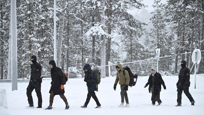 Lực lượng Biên phòng Phần Lan hộ tống những người di cư đến cửa khẩu quốc tế Raja-Jooseppi giữa Nga và Phần Lan, ngày 25-11. Ảnh: AP