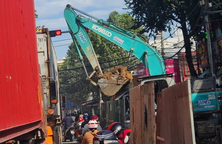 Người đi đường lo sợ khi nhìn thấy chiếc gầu xúc đầy đất lơ lửng ngay trên đầu
