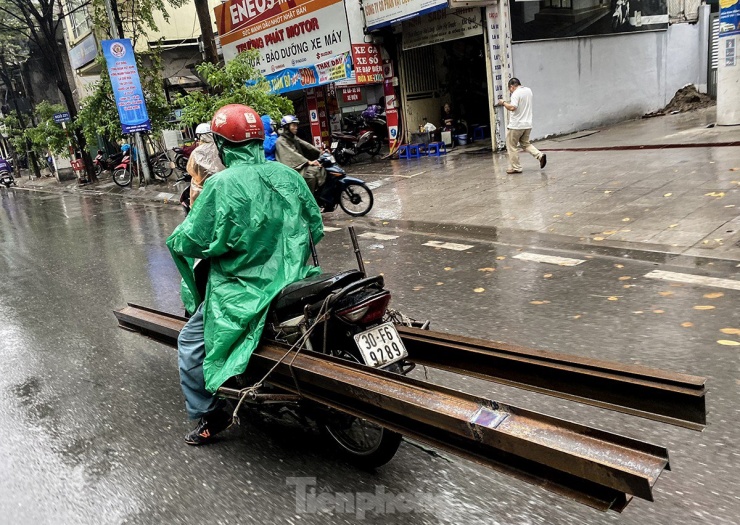 Ghi nhận sáng 1/12, dù trời mưa tầm tã, các phương tiện chở hàng cồng kềnh vẫn xuất hiện rất nhiều trên đường phố Hà Nội. Đường trơn trượt, đầu và cuối xe không có vật liệu che chắn, cảnh báo cho người đi đường.