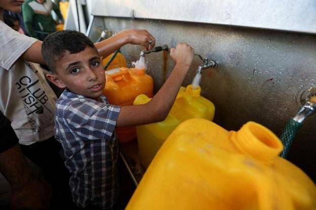 Cậu bé người Palestine đổ đầy nước. Ảnh: Reuters