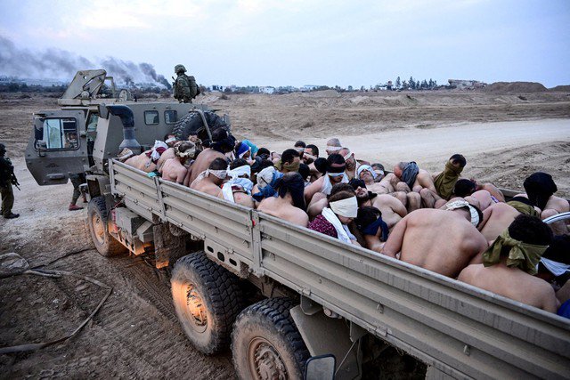 Binh sĩ Israel đứng cạnh xe tải chở tù nhân Palestine ở Dải Gaza. Ảnh: Reuters